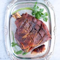 Easy Roasted Pork Shoulder with crispy skin on a silver platter with parsley garnish