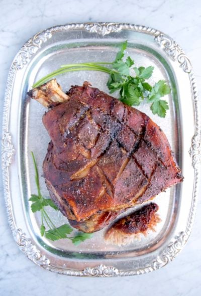 Easy Roasted Pork Shoulder with crispy skin on a silver platter with parsley garnish