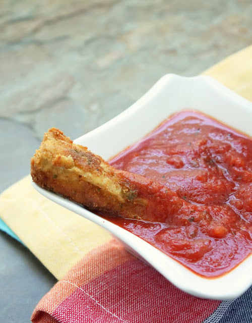Keto eggplant fries dipped in low carb marinara sauce in a white dish
