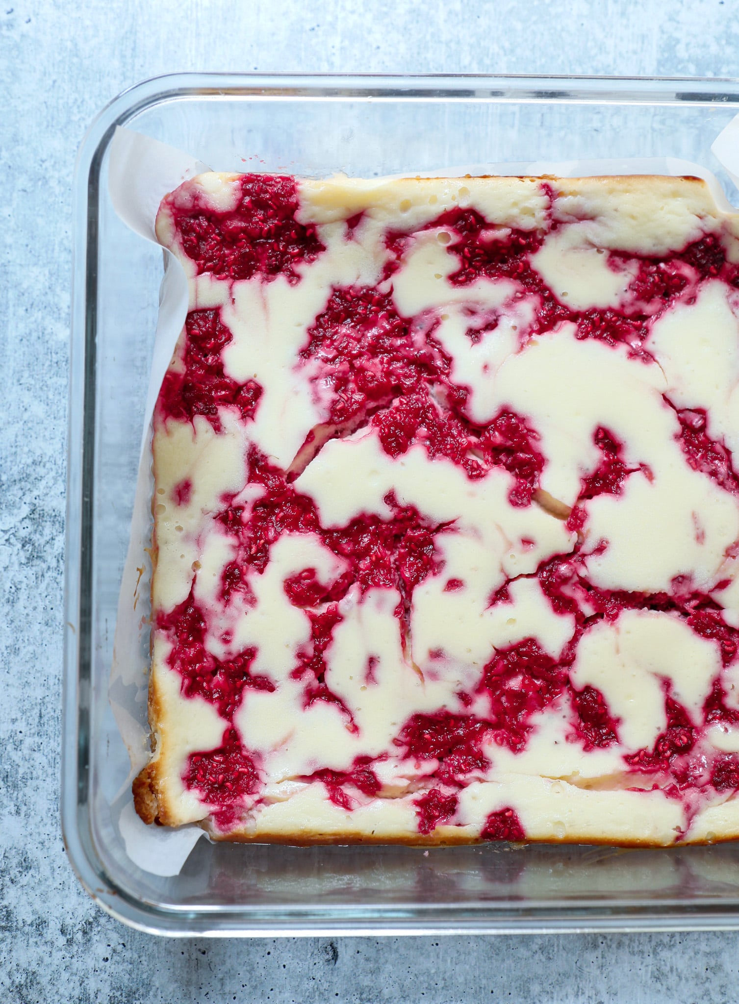 Top view of glass pan of keto raspberry cheesecake before it is cut into squares for serving