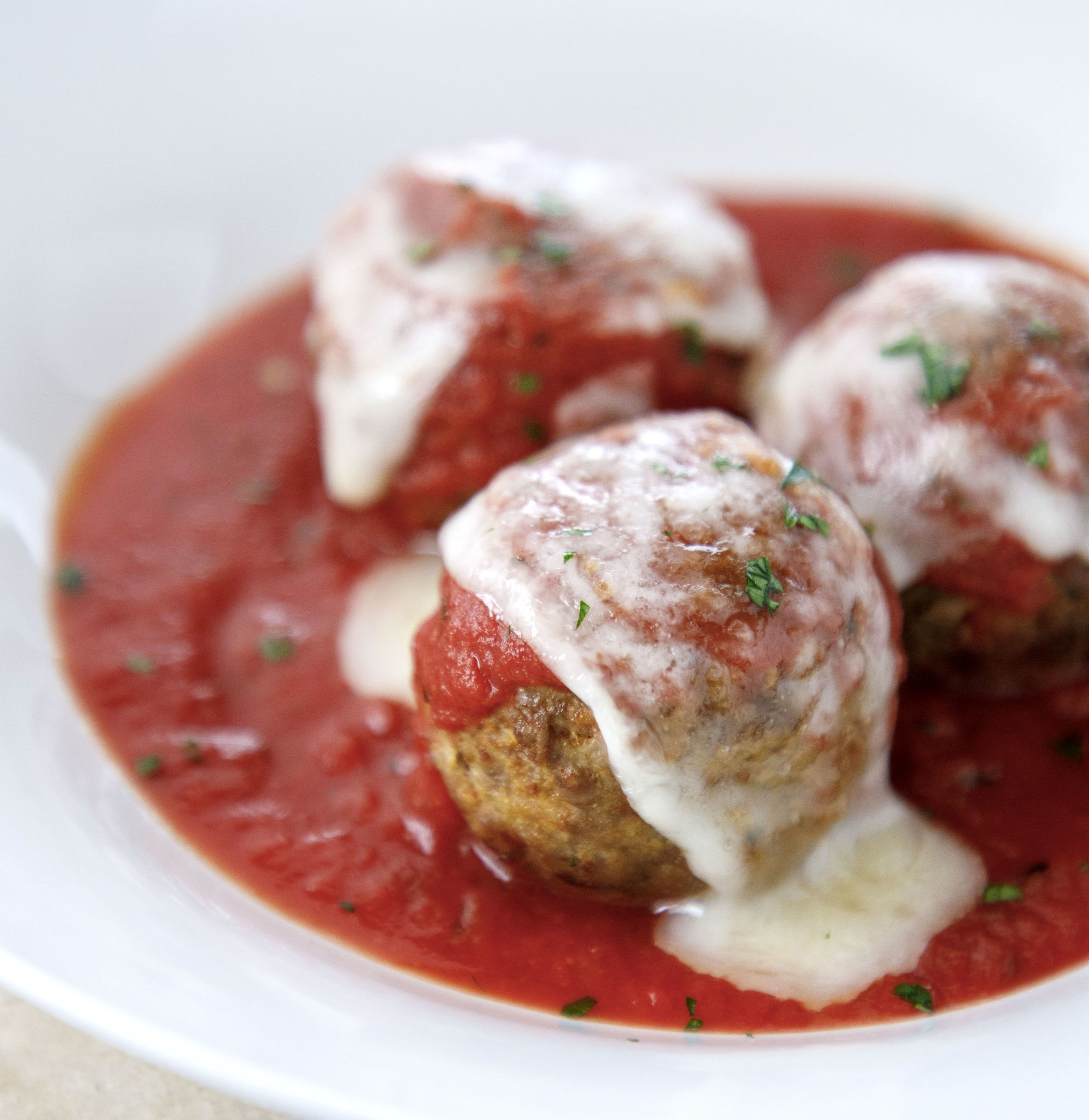 closeup of keto meatballs with tomato sauce and melted mozzarella cheese