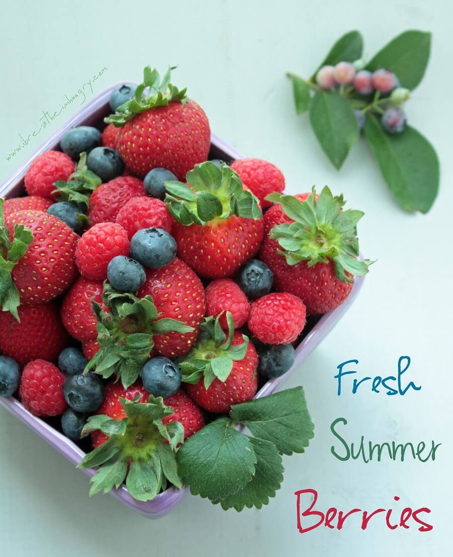 Purple berry basket full of fresh strawberries, blueberries, and raspberries