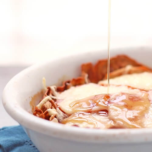 Keto Monte Cristo casserole in a white dish with syrup being drizzled over it.