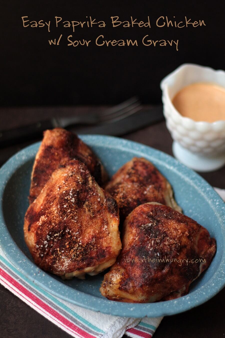 Super crispy Keto Baked Chicken Thighs in a blue enamelware platter with sour cream gravy on the side