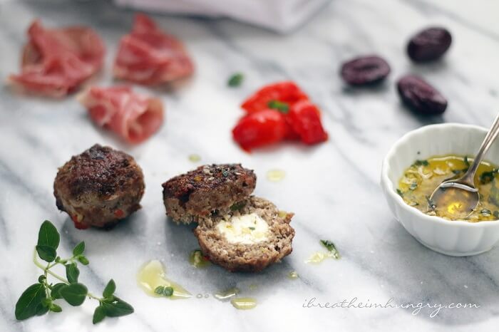 keto feta stuffed meatballs on a marble board with garlic oil and oregano garnish