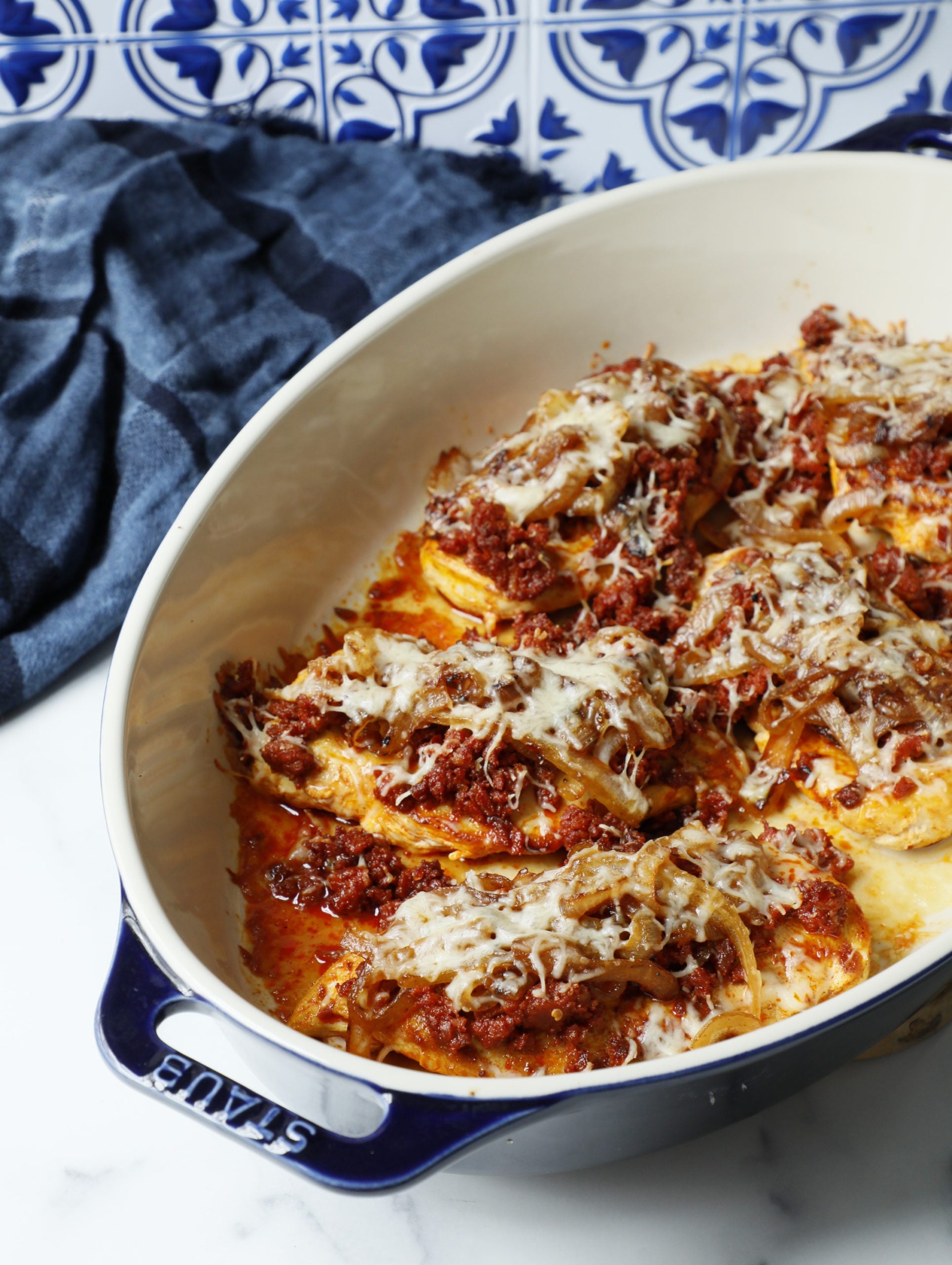 chori pollo in a navy and cream staub casserole dish with a blue napkin in the background