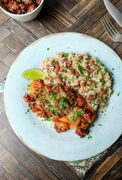 chori pollo on a light blue plate with rice and beans and a cilantro garnish