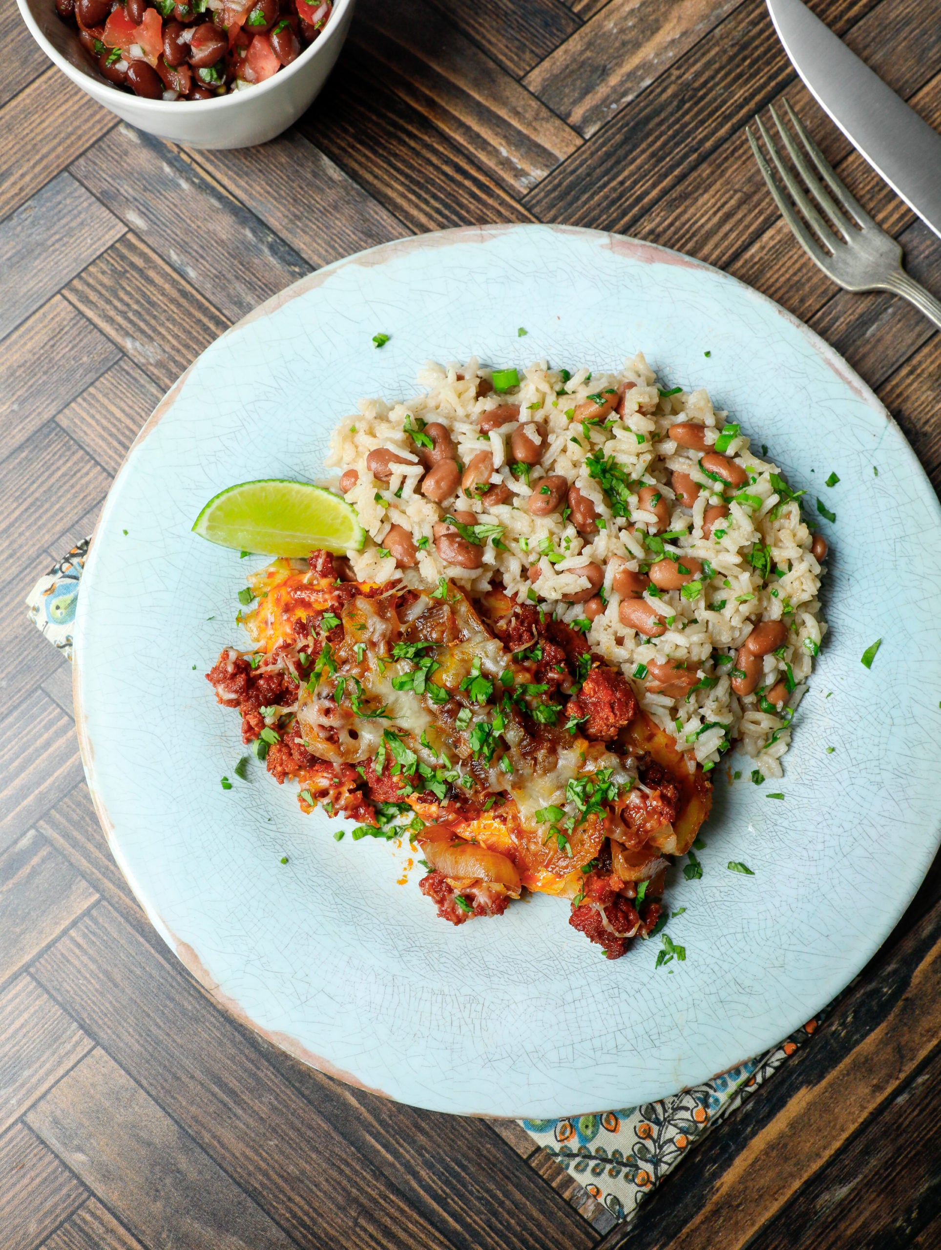 chori pollo on a light blue plate with rice and beans and a cilantro garnish