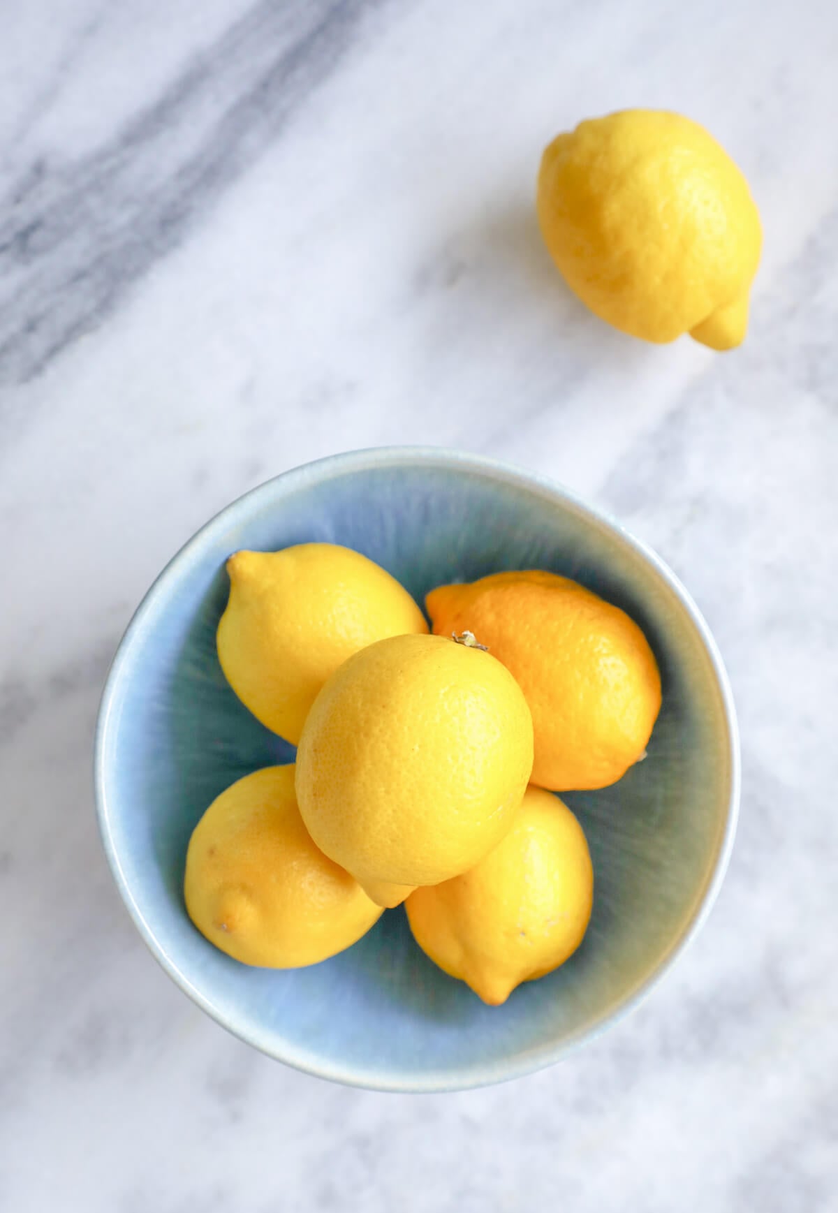 blue porcelain bowl of lemons on a marble background