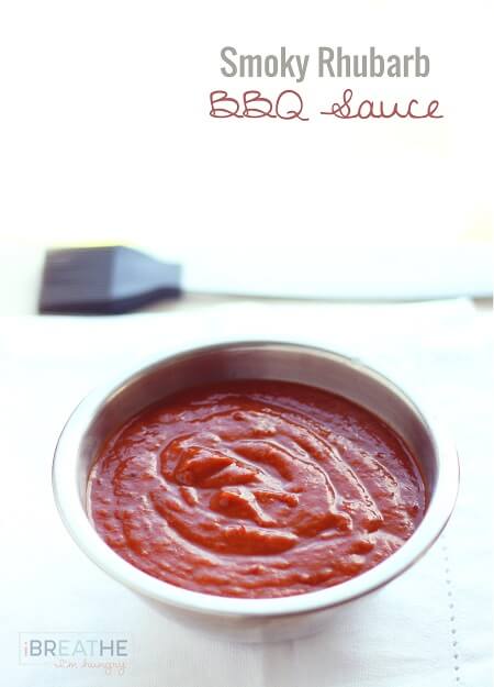Smoky Rhubarb BBQ sauce in a small stainless bowl on a white napkin with a silicon basting brush in the background