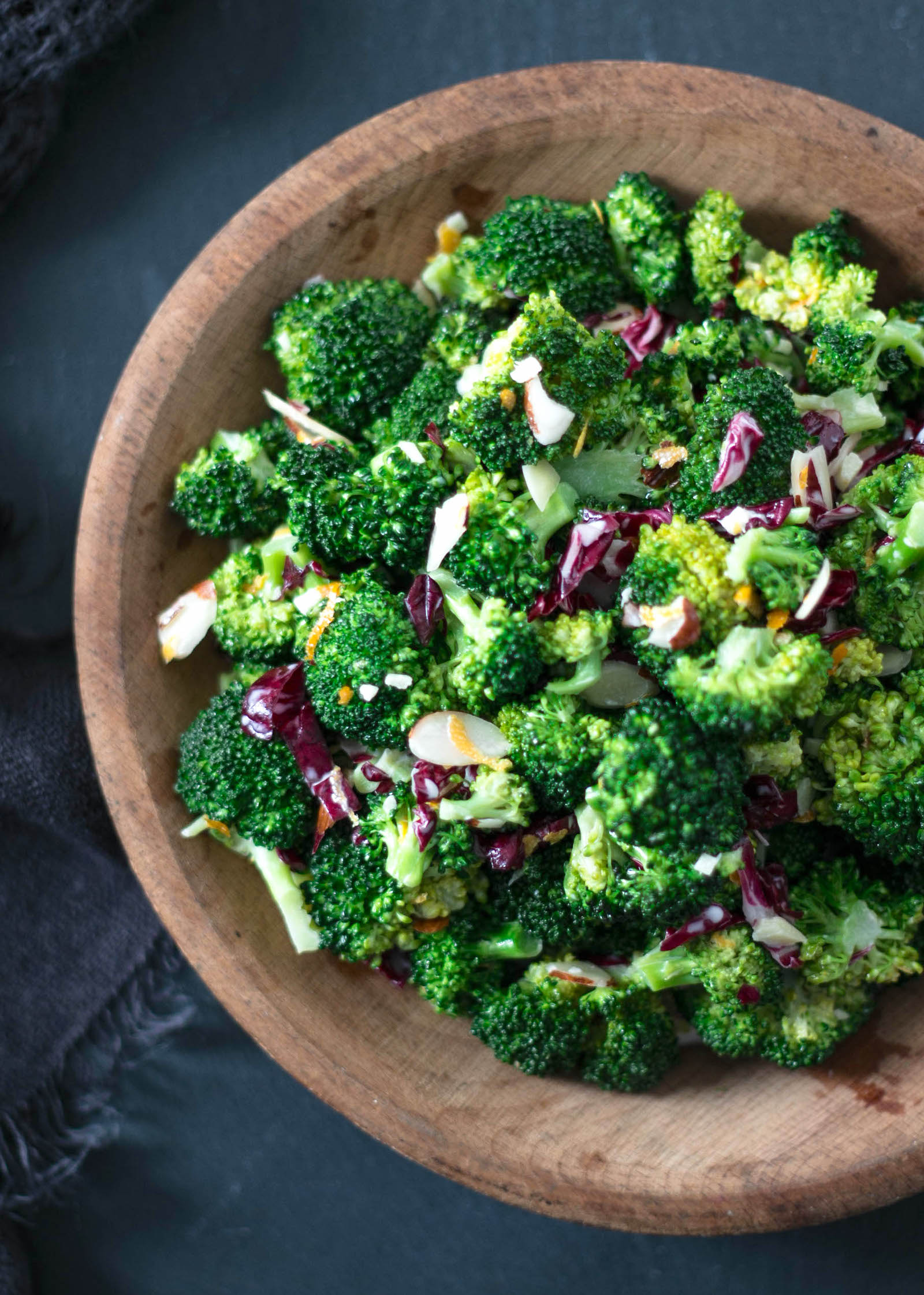 Top shot of a healthy keto broccoli salad in a wooden bowl garnished with sliced almonds