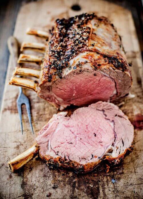 Roasted standing rib roast sliced on wooden cutting board