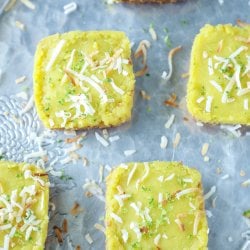 Keto Coconut Lime Bars sprinkled with coconut on a grey background