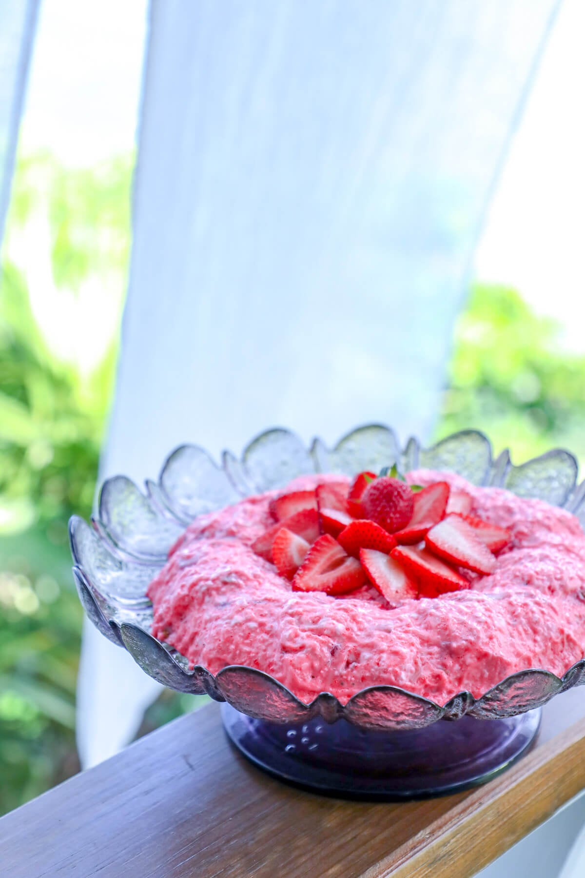keto strawberry jello salad on railing with white curtain