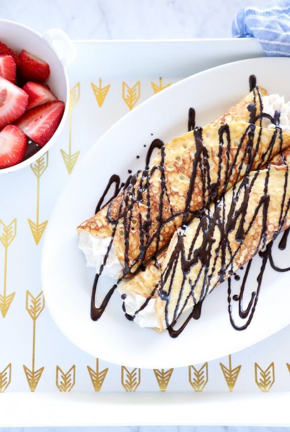 Keto Cannoli Stuffed Crepes on white tray with gold arrows