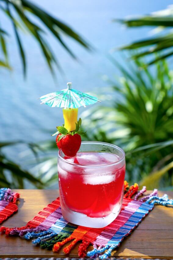 Easy Keto Rum Punch with strawberry and pineapple garnish