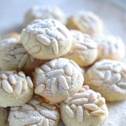 keto pignoli cookies on a white cake plate