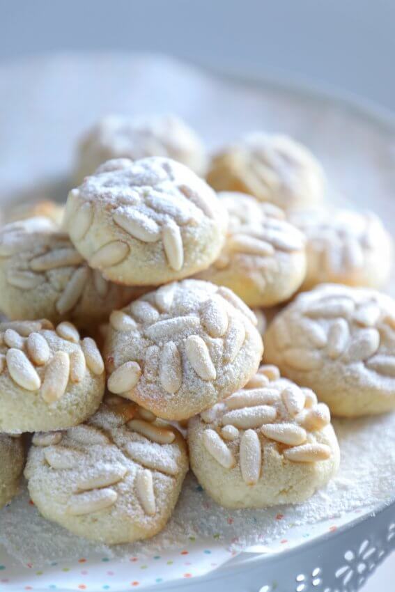 keto pignoli cookies on a white cake plate