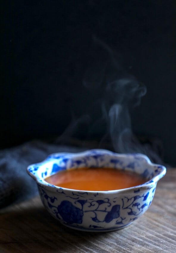 keto roasted tomato & garlic soup on wooden board with black background