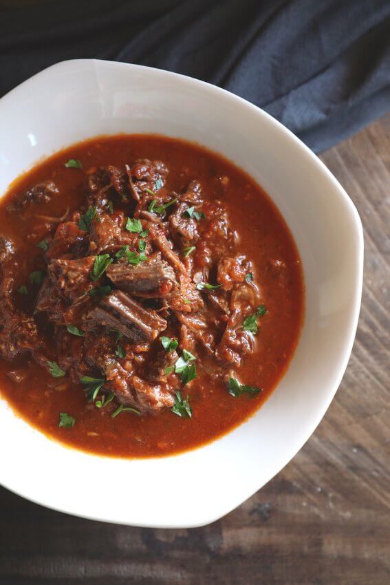Keto Short Rib Ragu in a white serving bowl on a wooden board