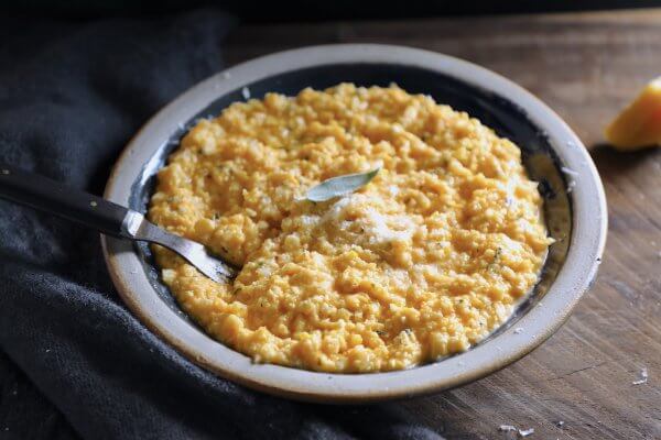 Keto butternut squash risotto in a blue pottery plate on a wooden board