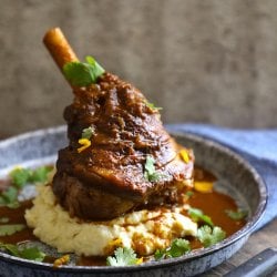 keto lamb shank shown with cauliflower puree on a blue granite enamelware plate