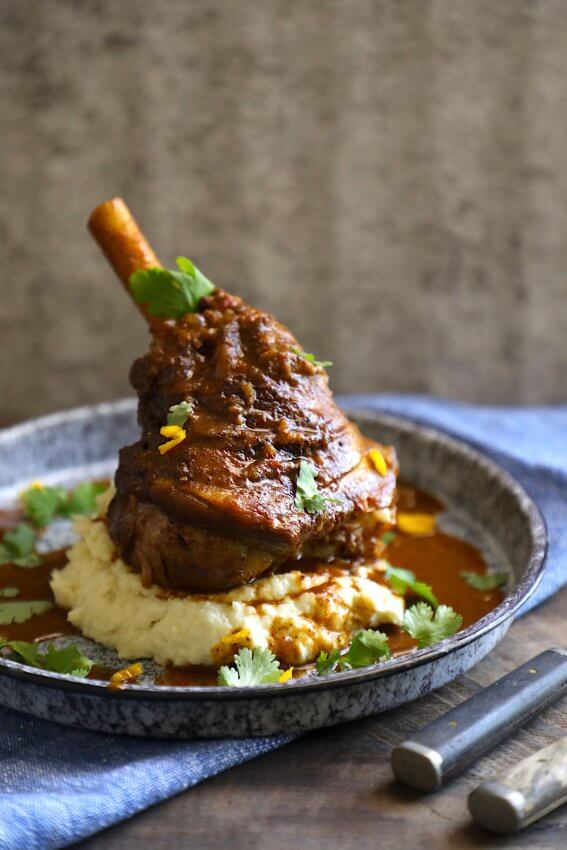 keto lamb shank shown with cauliflower puree on a blue granite enamelware plate