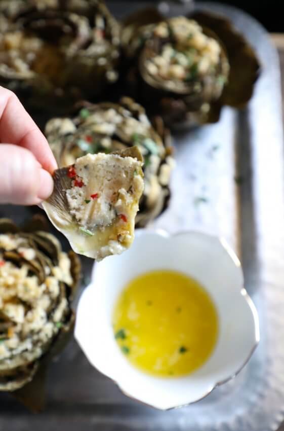 Fingers holding a leaf of Keto Stuffed Artichokes