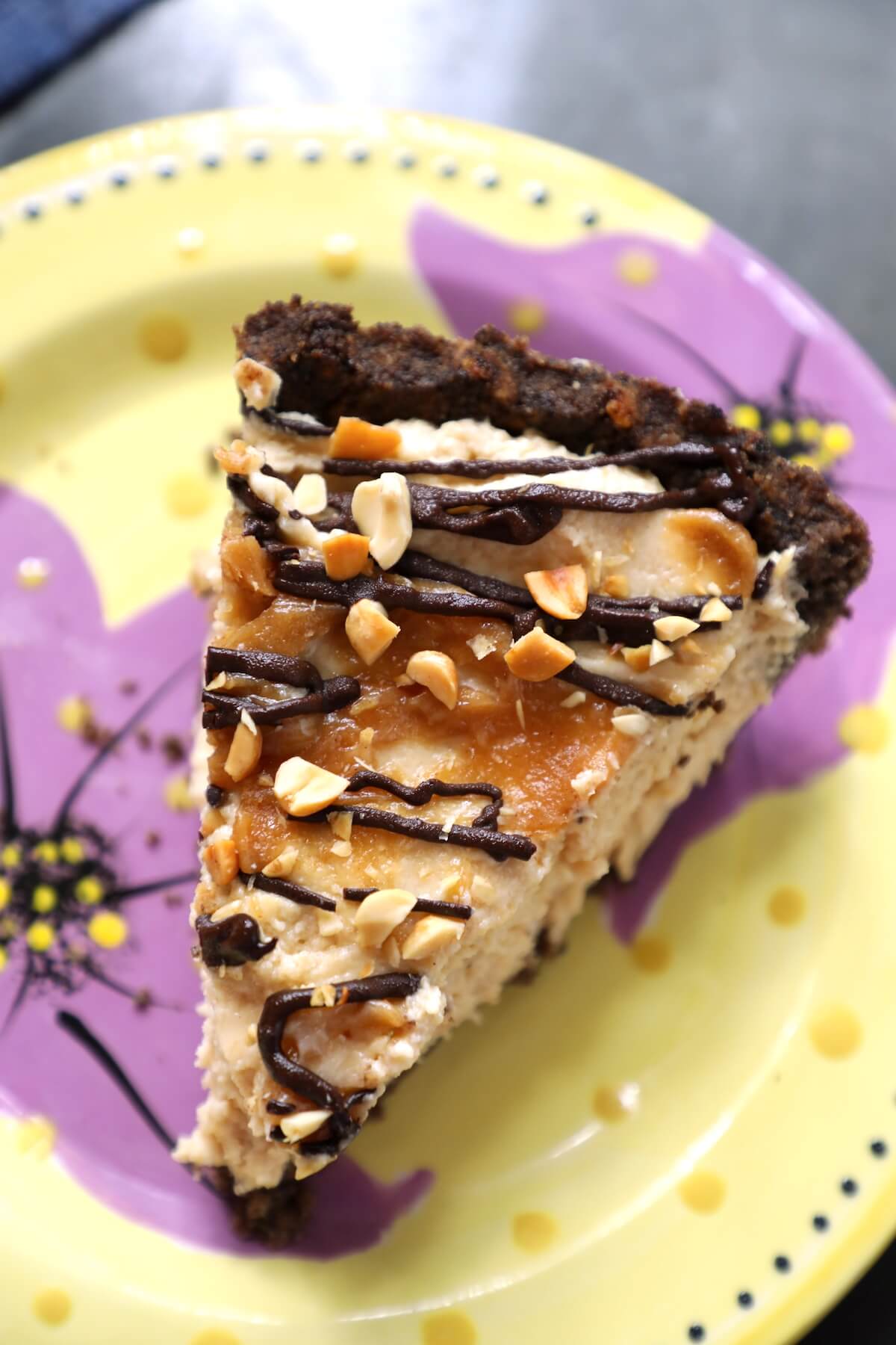 Top view of a slice of Keto Peanut Butter & Chocolate Pie on a yellow pottery plate with purple flowers on it.
