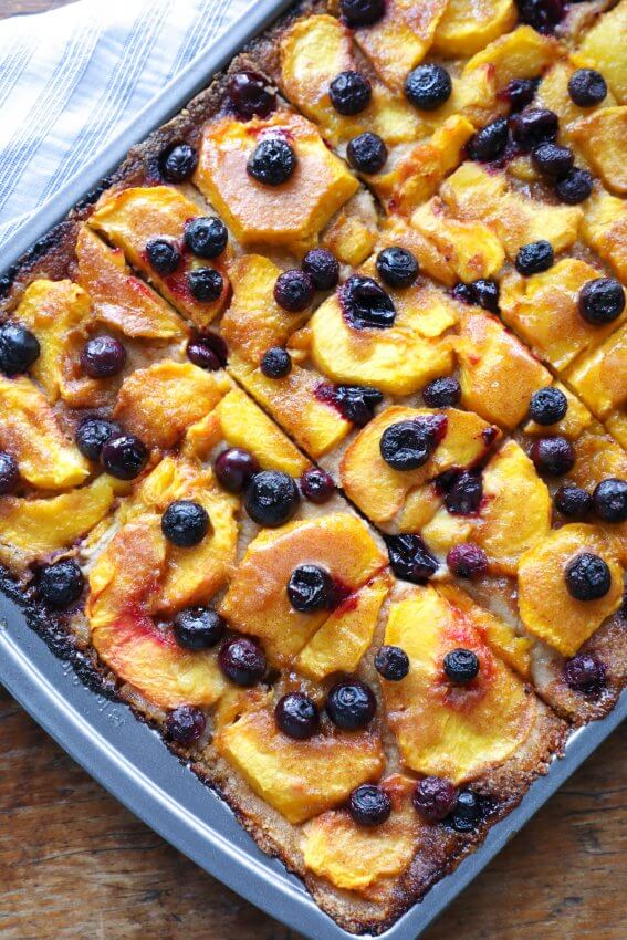 keto peach and blueberry slab pie on a cookie sheet shown after baking and golden brown
