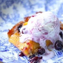 Keto Peach and Blueberry Slab Pie on a blue and white plate with a scoop of mixed berry ice cream on top