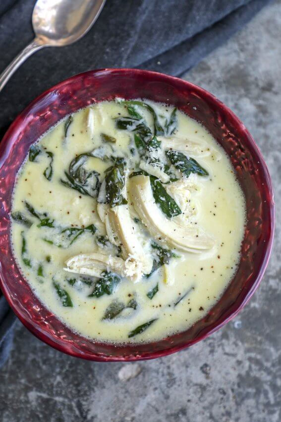 keto chicken Florentine soup in a magenta bowl with an antique spoon on a grey napkin in the background