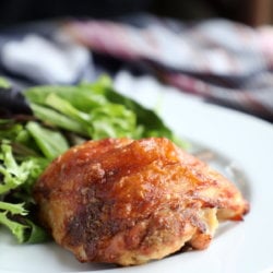 Keto Caesar Baked Chicken on a white plate with salad in the background