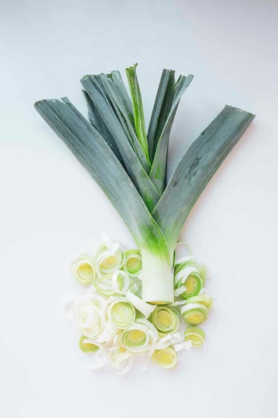 leeks partially sliced on a white background