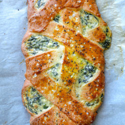 Cheesy Keto Spinach Calzone shown whole and on a parchment lined baking sheet