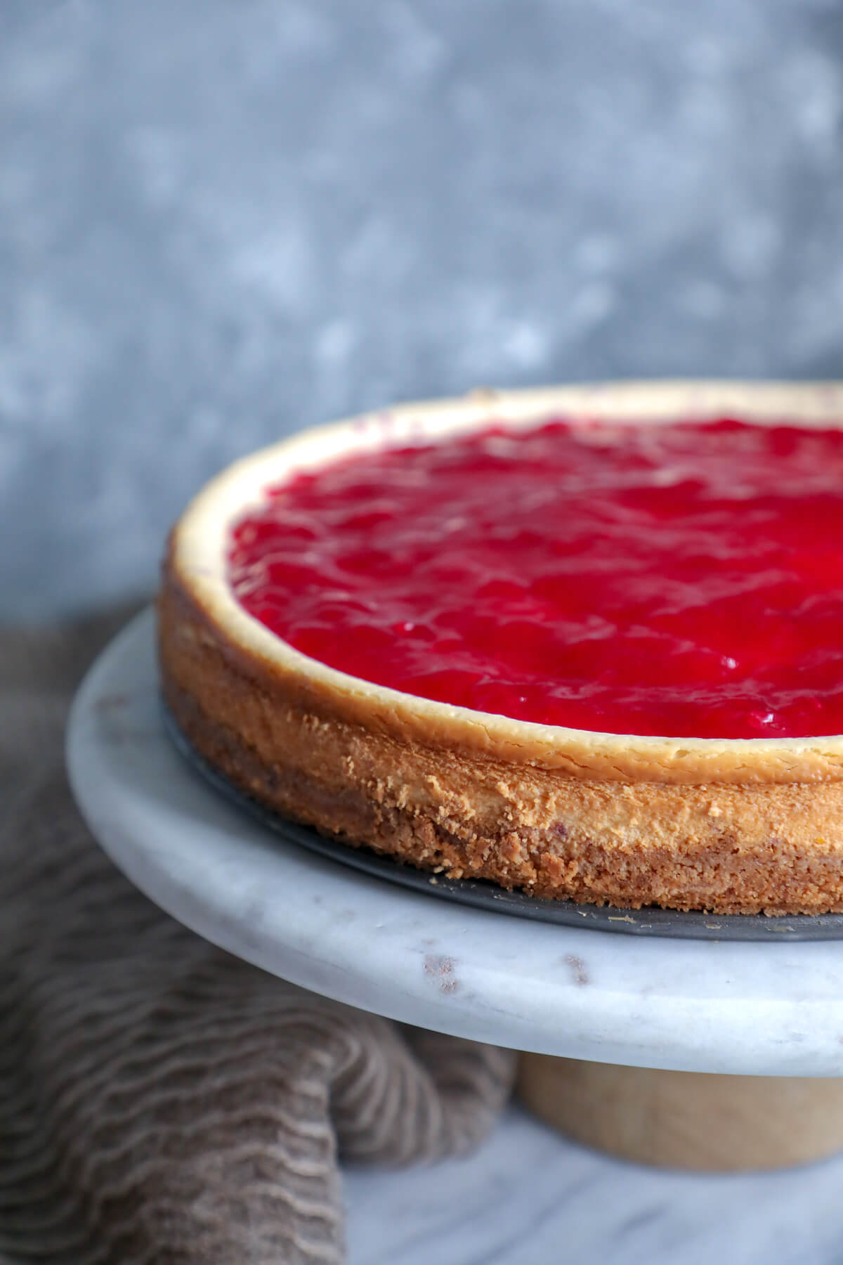 Keto cranberry orange cheesecake on a marble cake pedestal