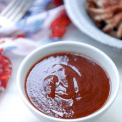 Keto barbecue sauce with pulled pork in the background