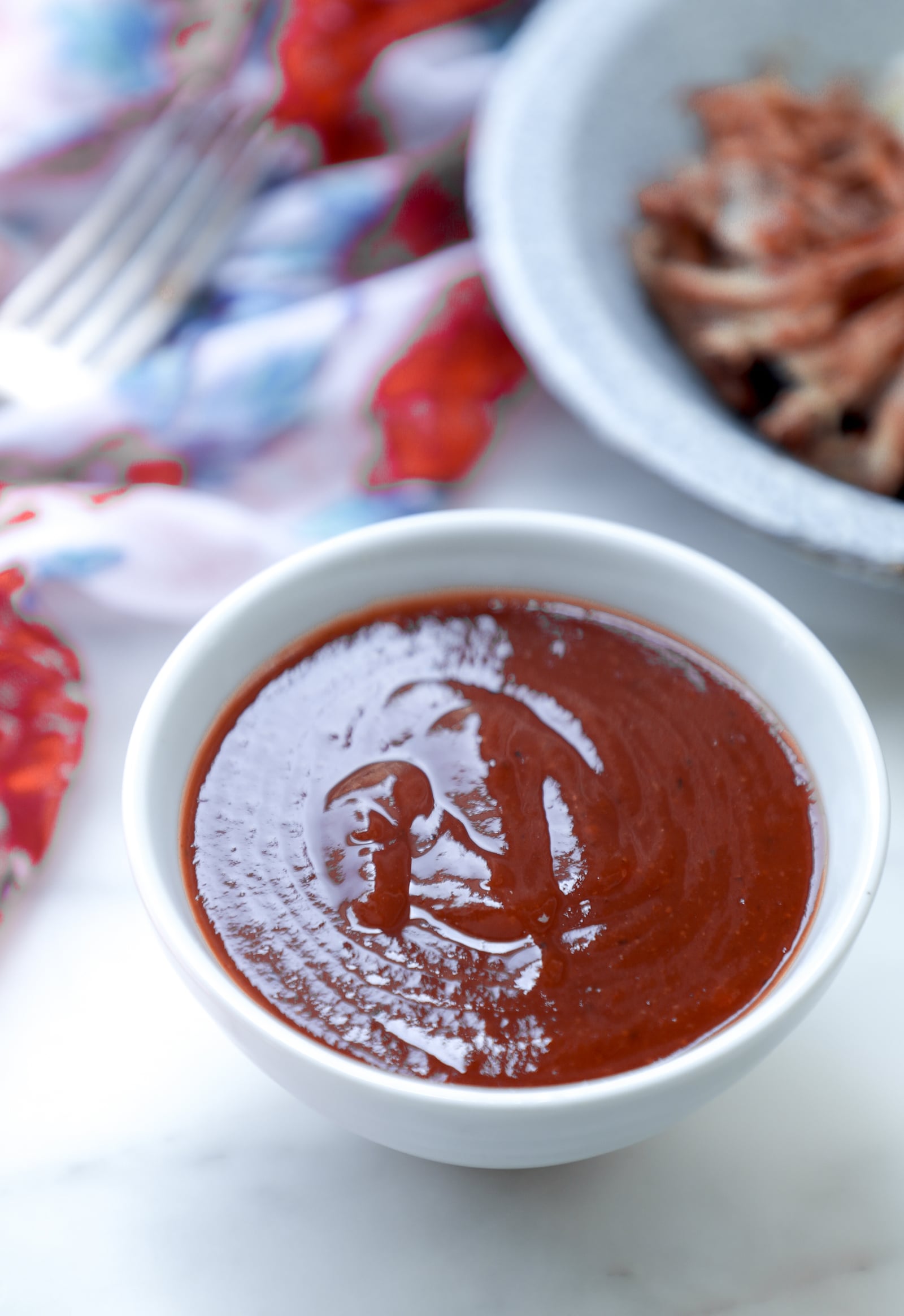 Keto barbecue sauce with pulled pork in the background