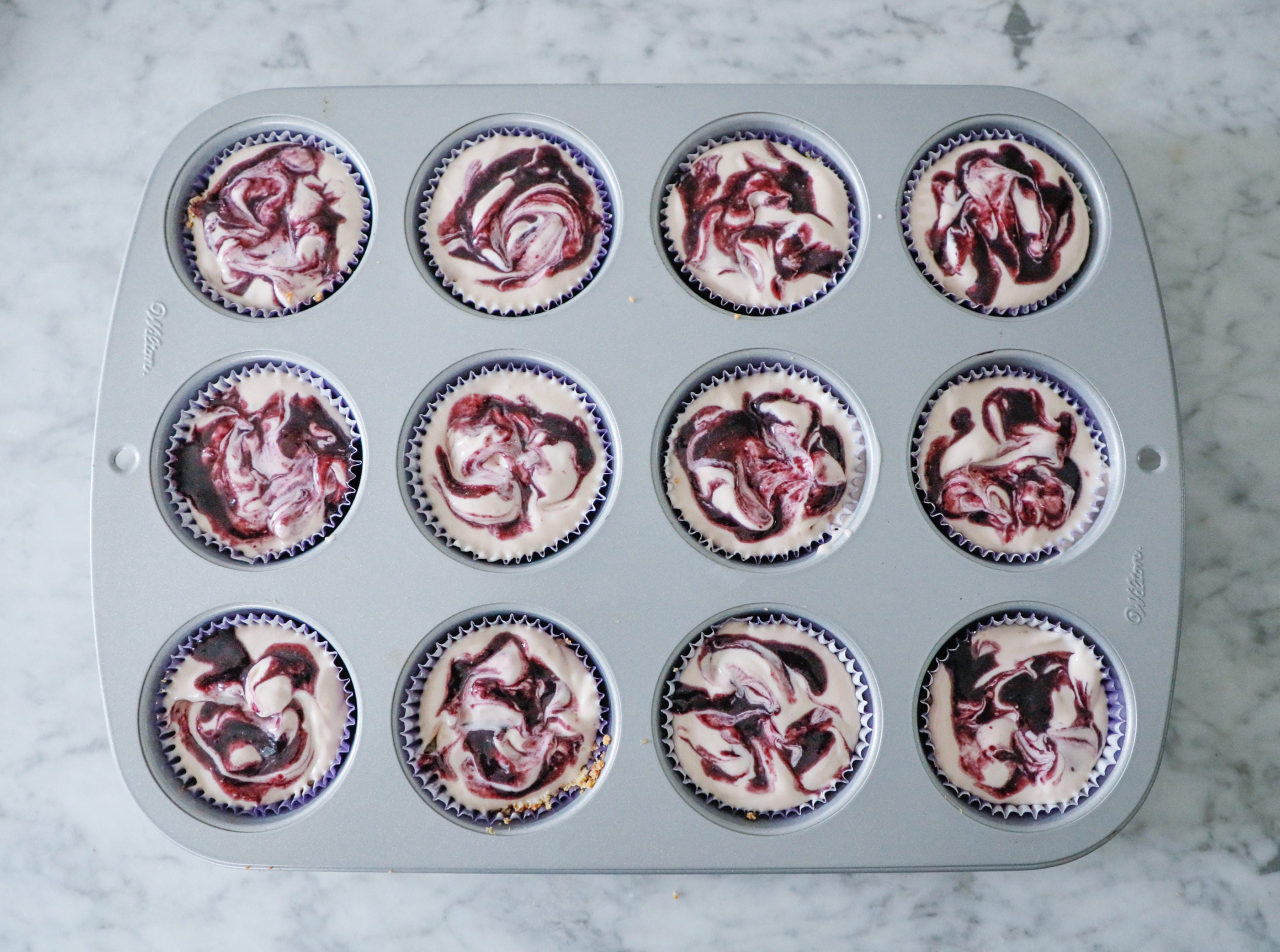 cheesecakes in a muffin tin before baking