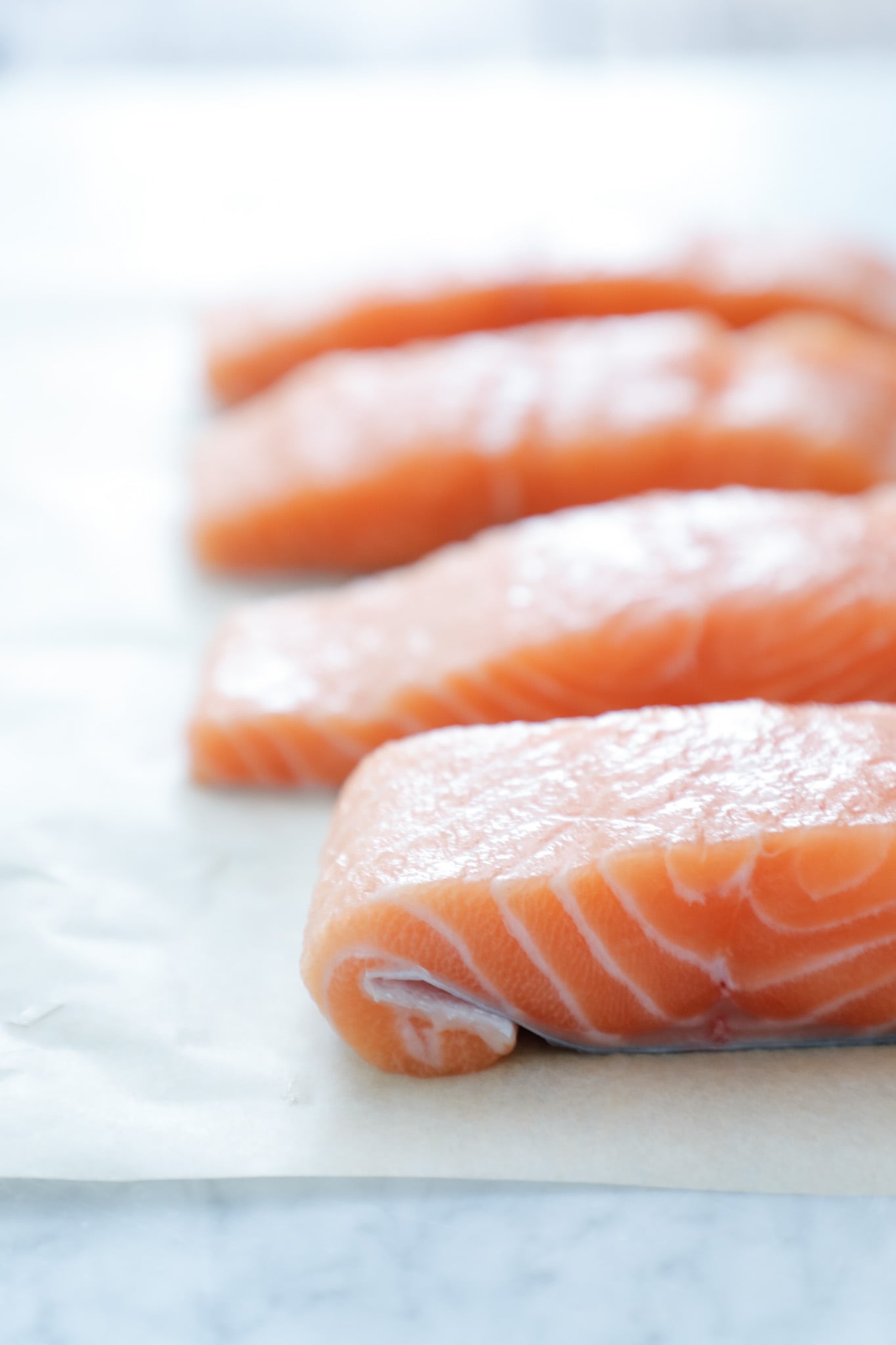 raw Salmon fillet on parchment paper folded over so it cooks more evenly. 