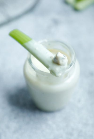 Keto Blue cheese dressing in a glass jar with a piece of celery on top that has been dipped into it