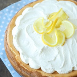 keto lemon cheesecake with whipped cream and lemon garnish on a blue and white napkin