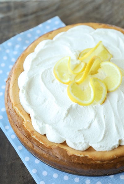 keto lemon cheesecake with whipped cream and lemon garnish on a blue and white napkin