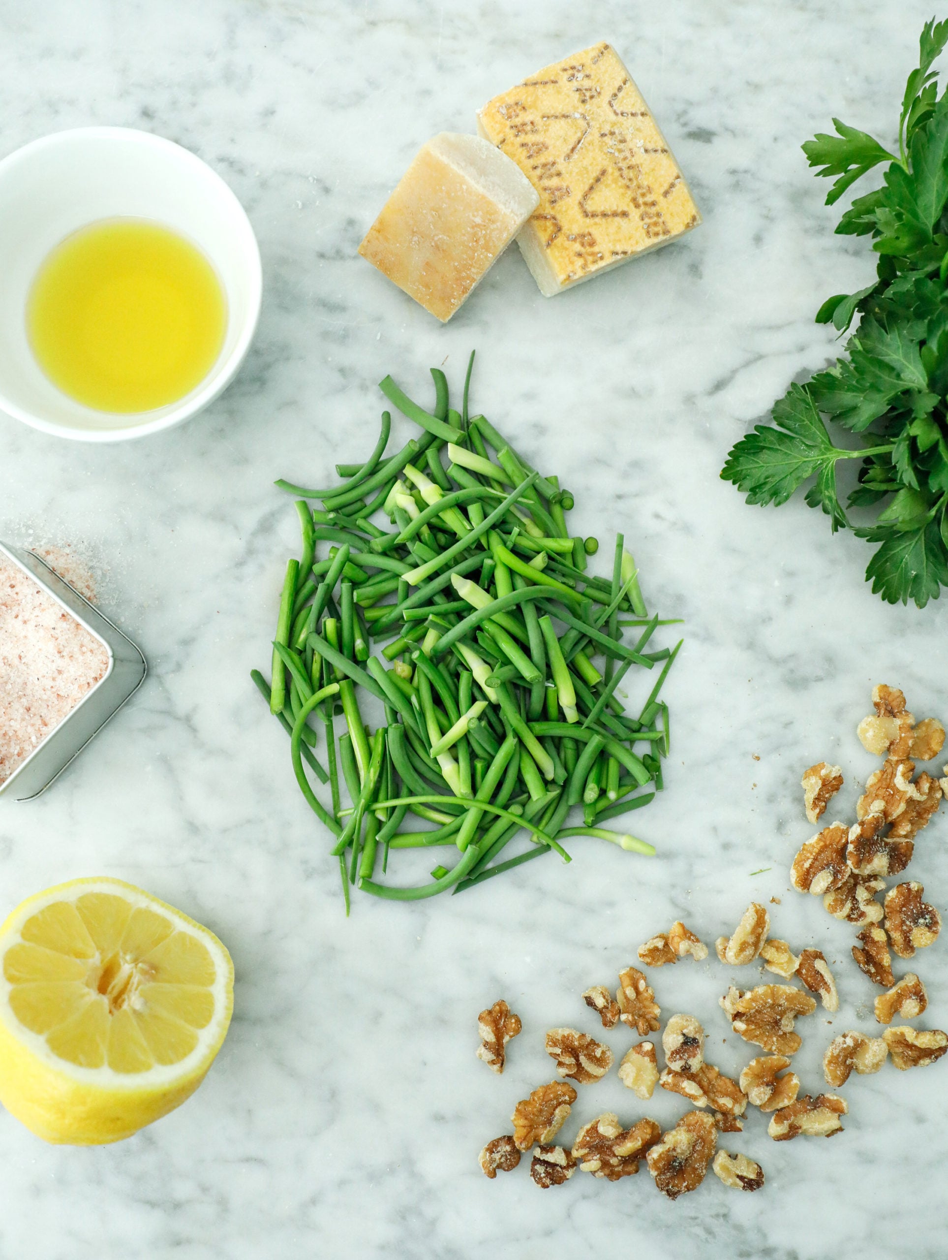 ingredients for garlic scape pesto on a white marble board