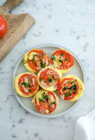6 high protein egg bites arranged on a grey plate on a marble background.