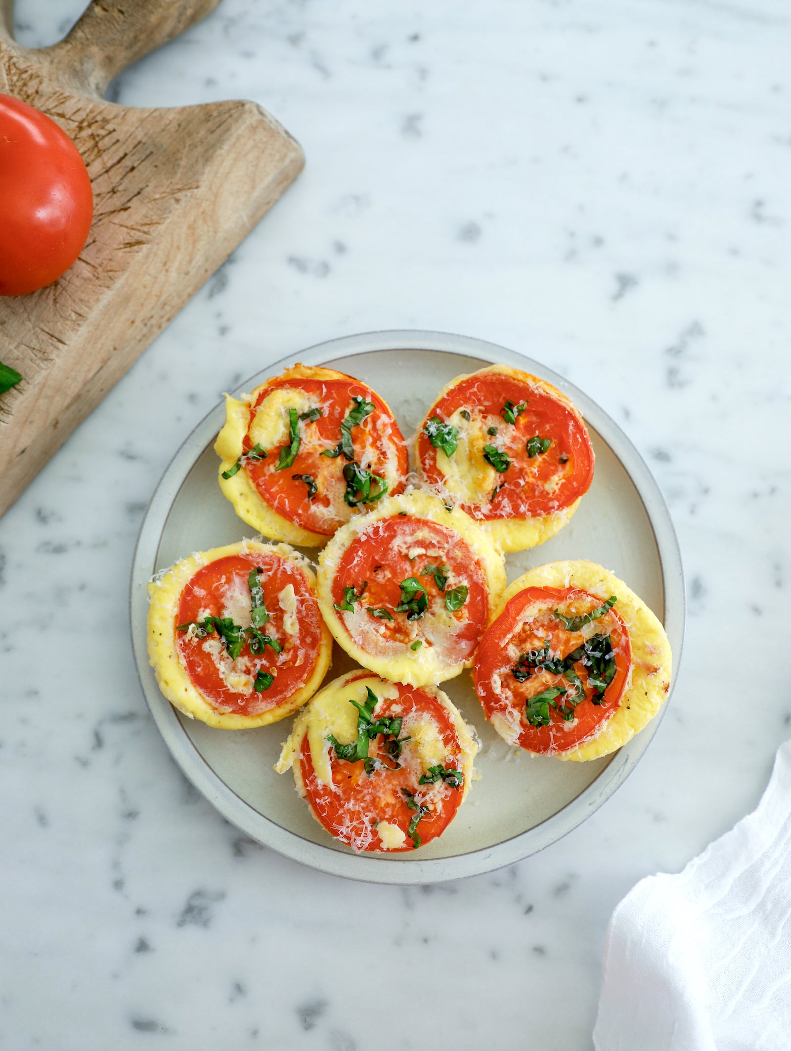 6 high protein egg bites arranged on a grey plate on a marble background.