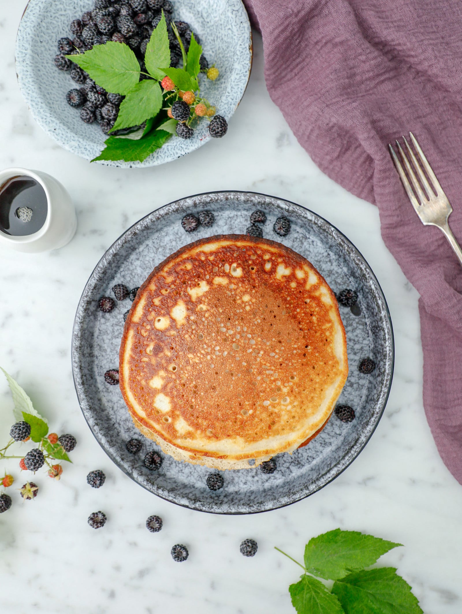 High protein pancakes on a speckled plates shot from above and garnished with black cap raspberries