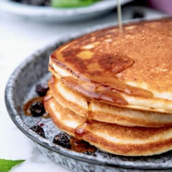 A stack of three high protein pancakes with maple syrup running down the side.