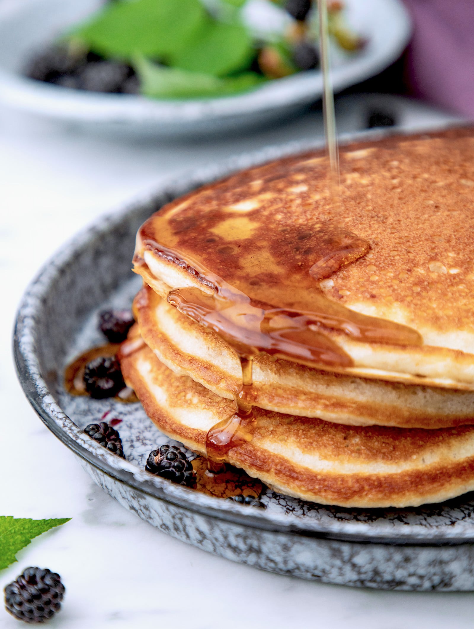 A stack of three high protein pancakes with maple syrup running down the side.