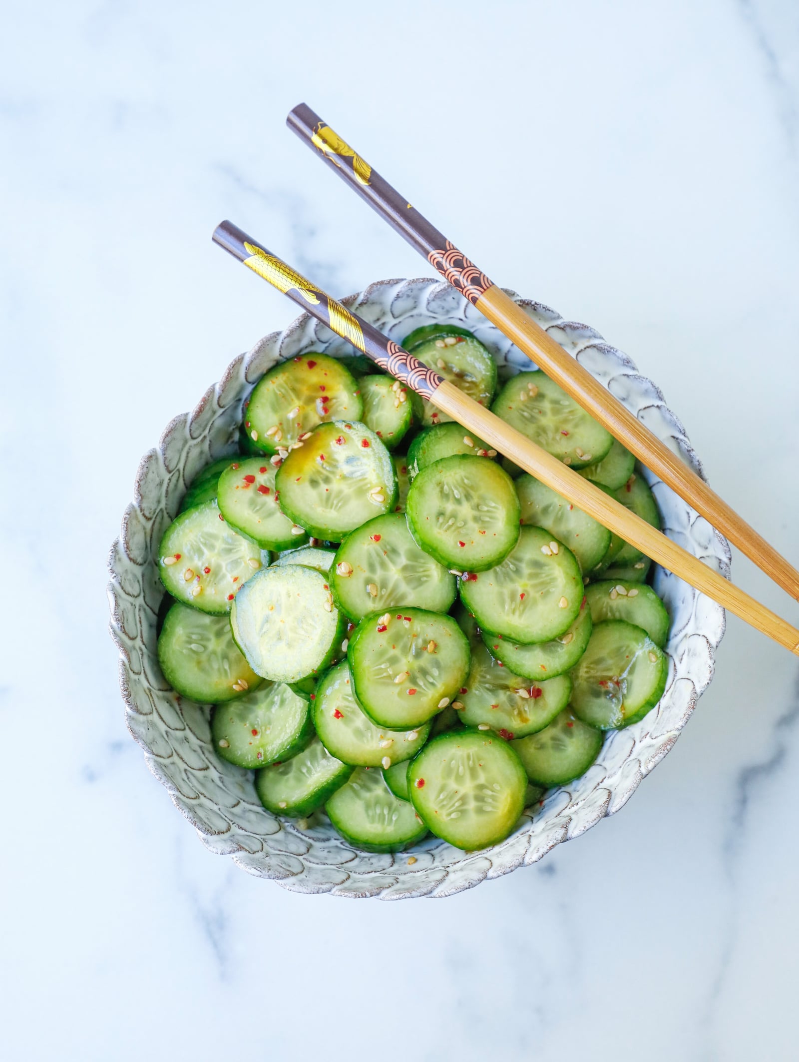 asian cucumber salad in a white bowl with chopsticks